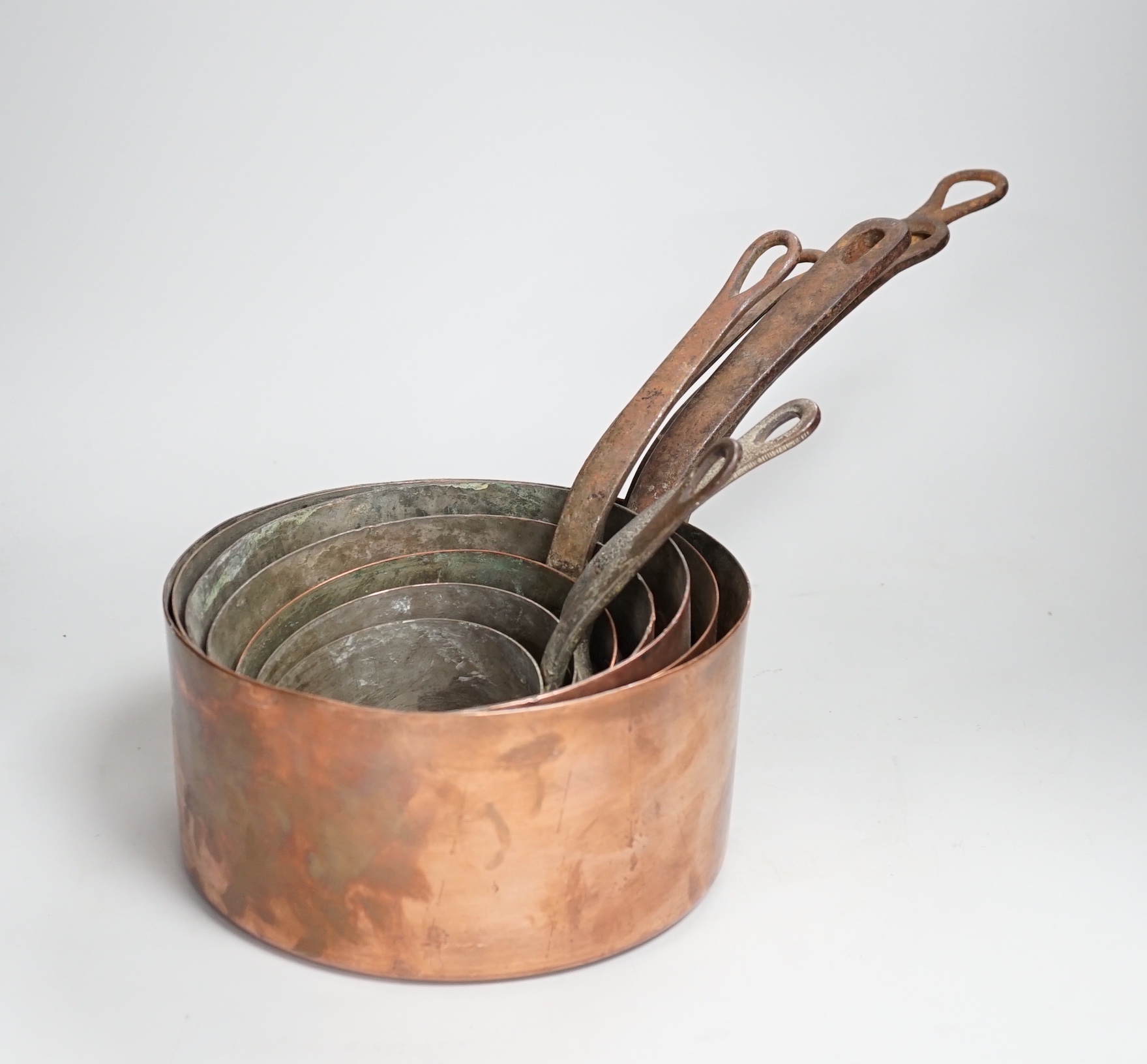 A graduated set of seven copper pans, the largest 47cm wide